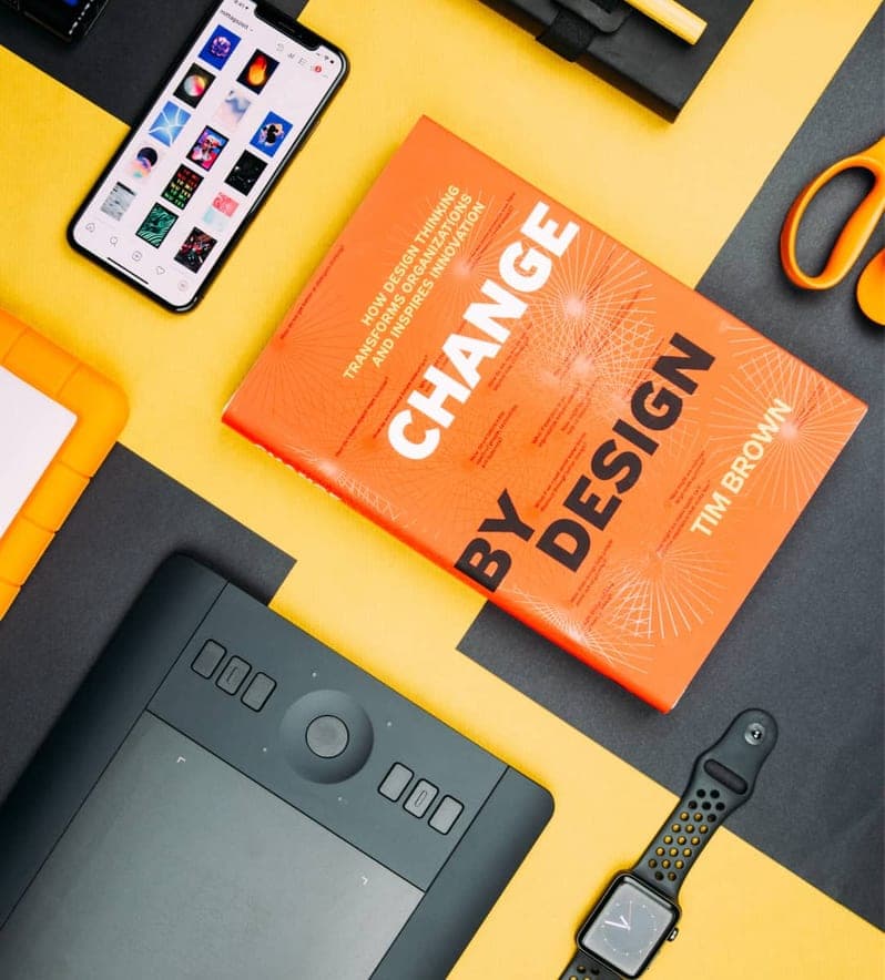 Change by Design by Tim Brown book beside smartphone on a table Change by Design by Tim Brown book beside smartphone on a table