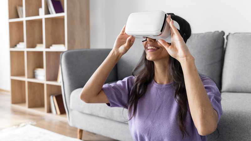 smiley woman using virtual reality headset home